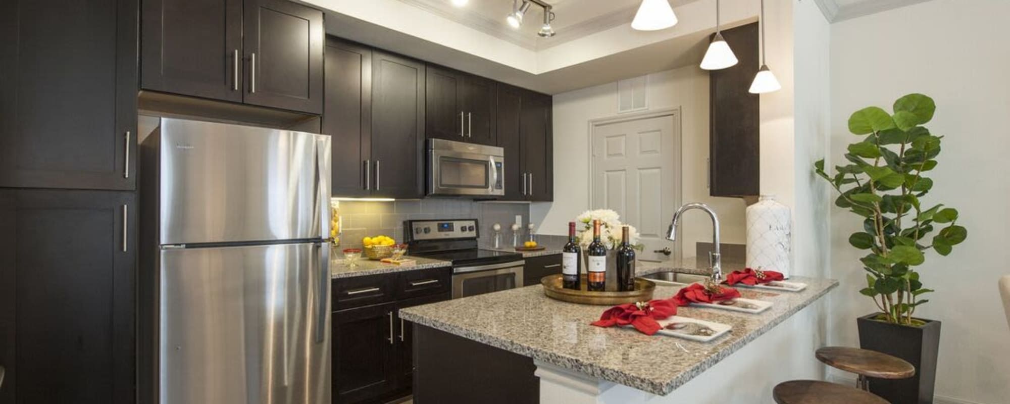 Upscale apartment kitchen with dark wood cabinets at The Crossing at Katy Ranch in Katy, Texas