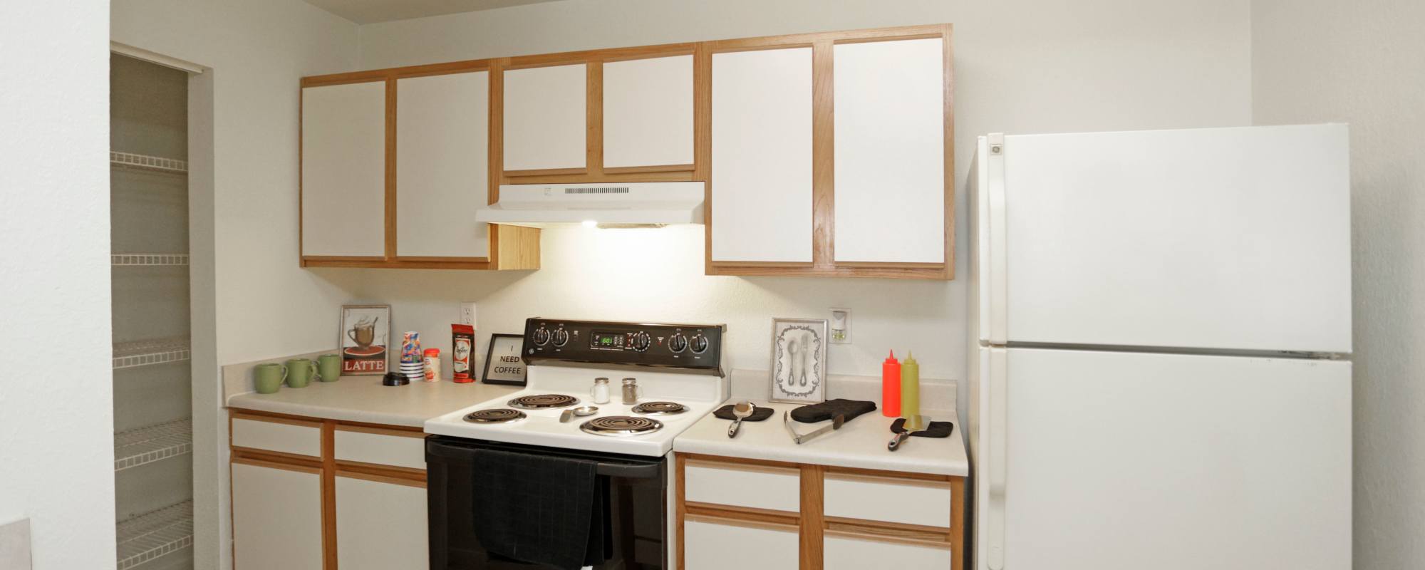 Kitchen with white and wood cabinets at North Oak Crossing in Kansas City, Missouri