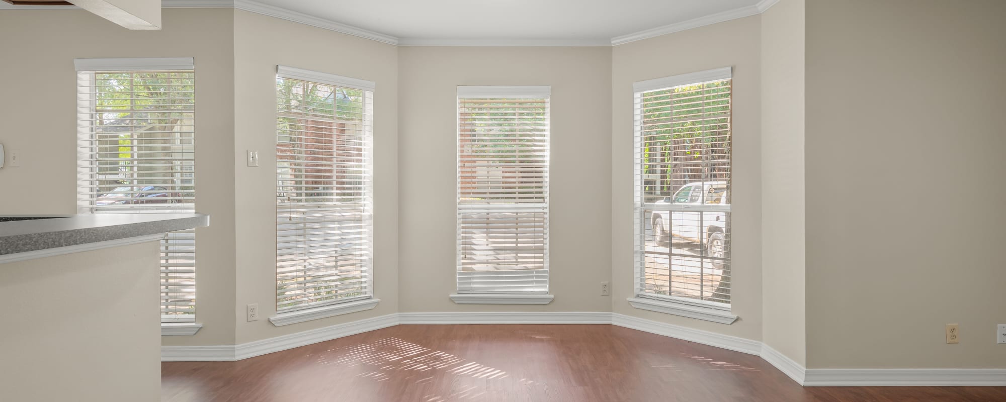 Bright living room with multiple windows and wooden flooring at The Willows in Shreveport, Louisiana