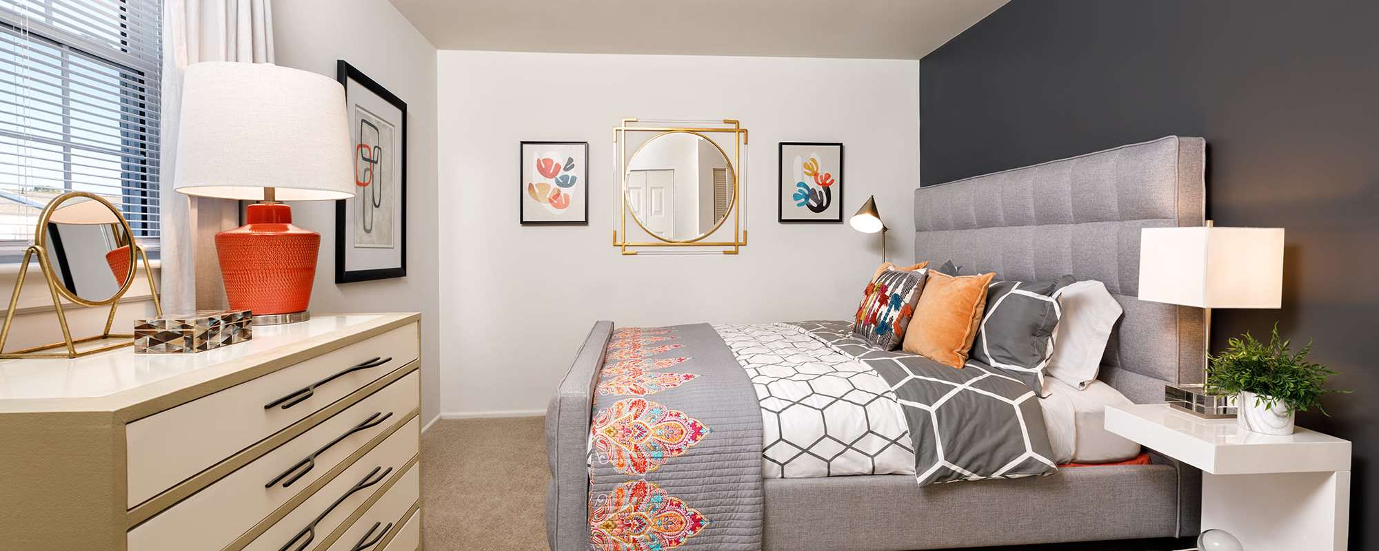 Bedroom with small side table and a large comfortable bed at The Landing at Oyster Point in Newport News, Virginia