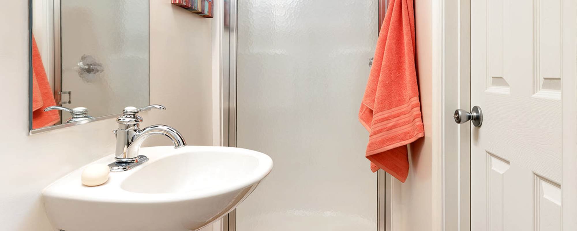 Bathroom with large mirror, waterfall faucet sink, shower and storage space at   at The Landing at Oyster Point in Newport News, Virginia