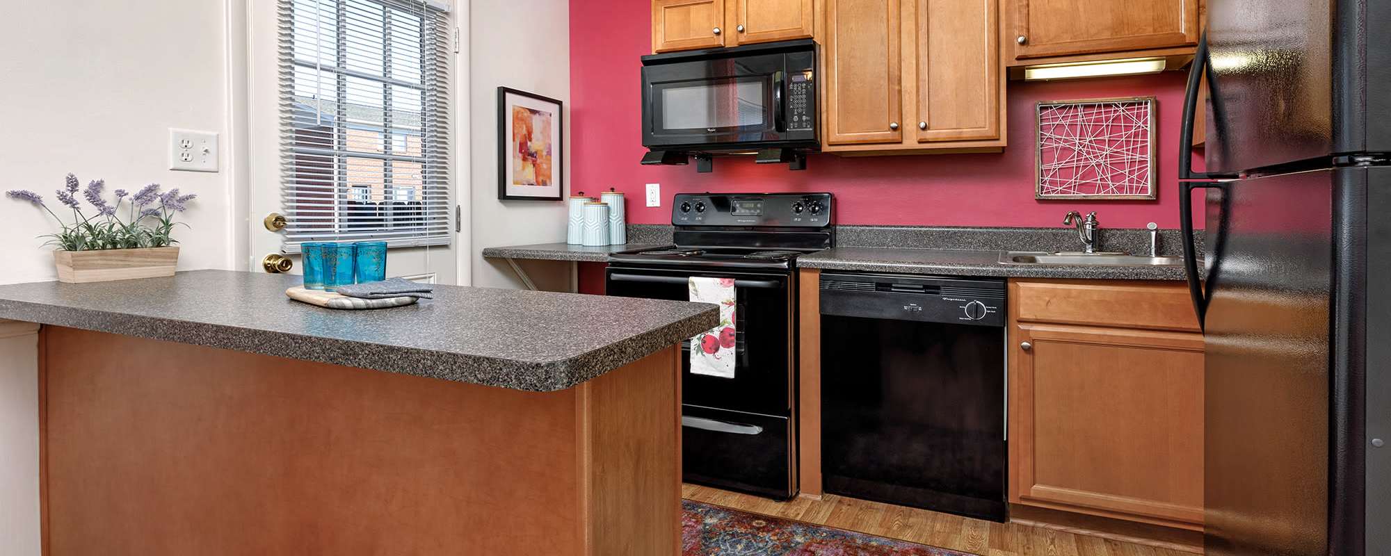 Kitchen with refrigerator, stove, oven and granite countertops at The Landing at Oyster Point in Newport News, Virginia