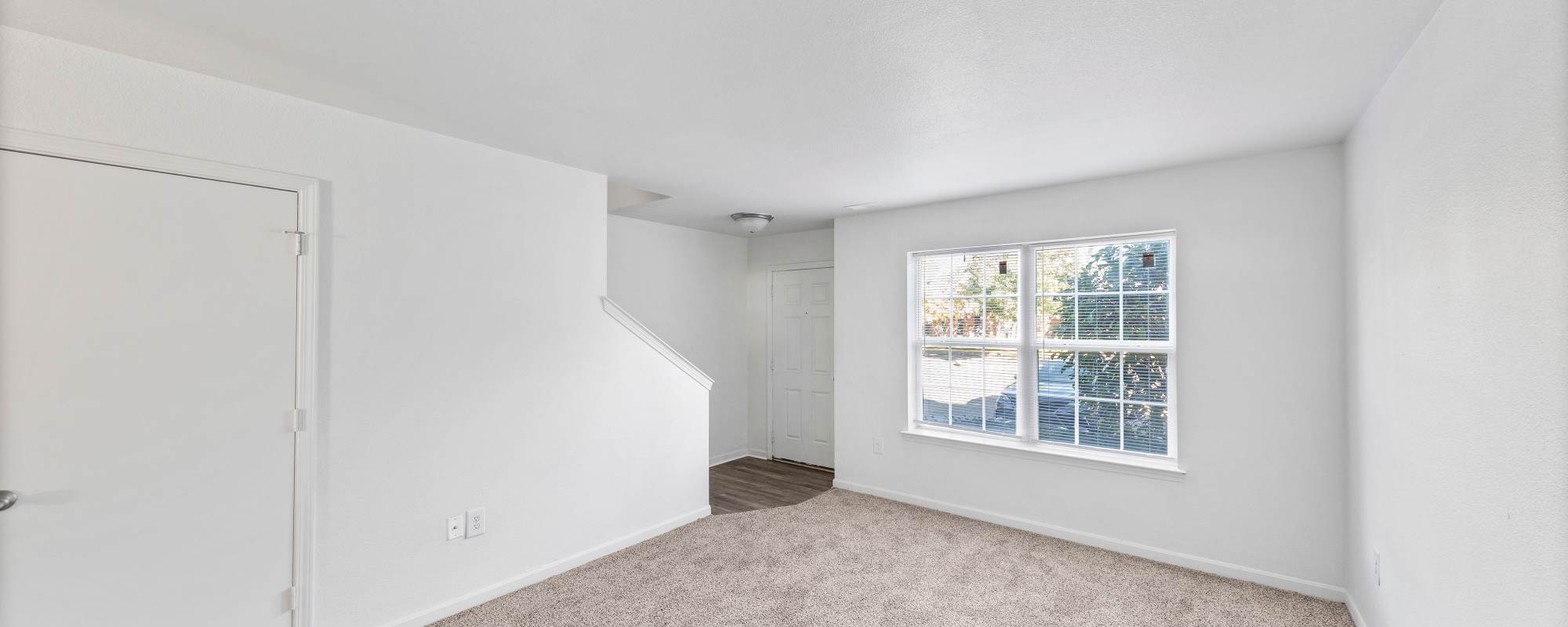 Empty living room space with staircase access at Tyler's Creek Townhomes in Fairfield, Ohio