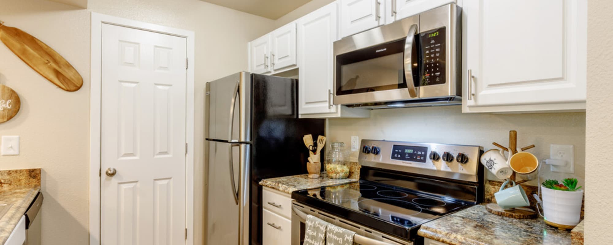 Fully equipped kitchen with granite countertops stainless steel appliances like a refrigerator, stove, and drawer microwave at UTE Creek Apartments in Longmont, Colorado, 