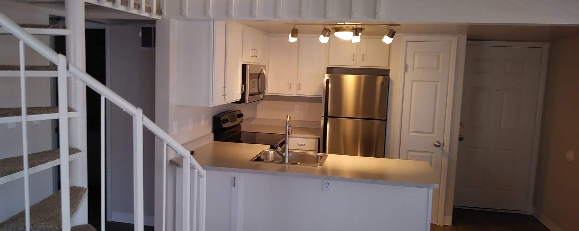 Modern kitchen with light and fridge at Victoria Inn Apartments in Longmont, Colorado