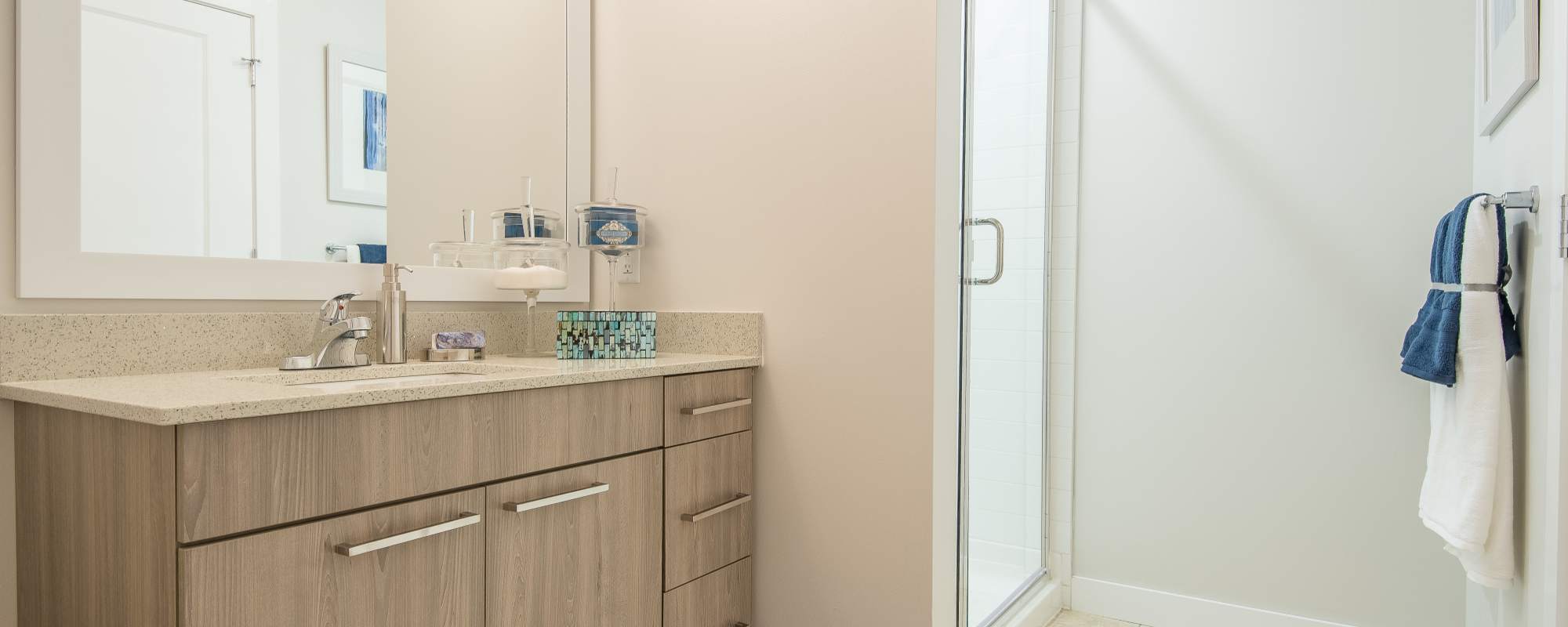 Bathroom sink and mirror with glass door shower area at Mayfair Reserve in Wauwatosa, Wisconsin