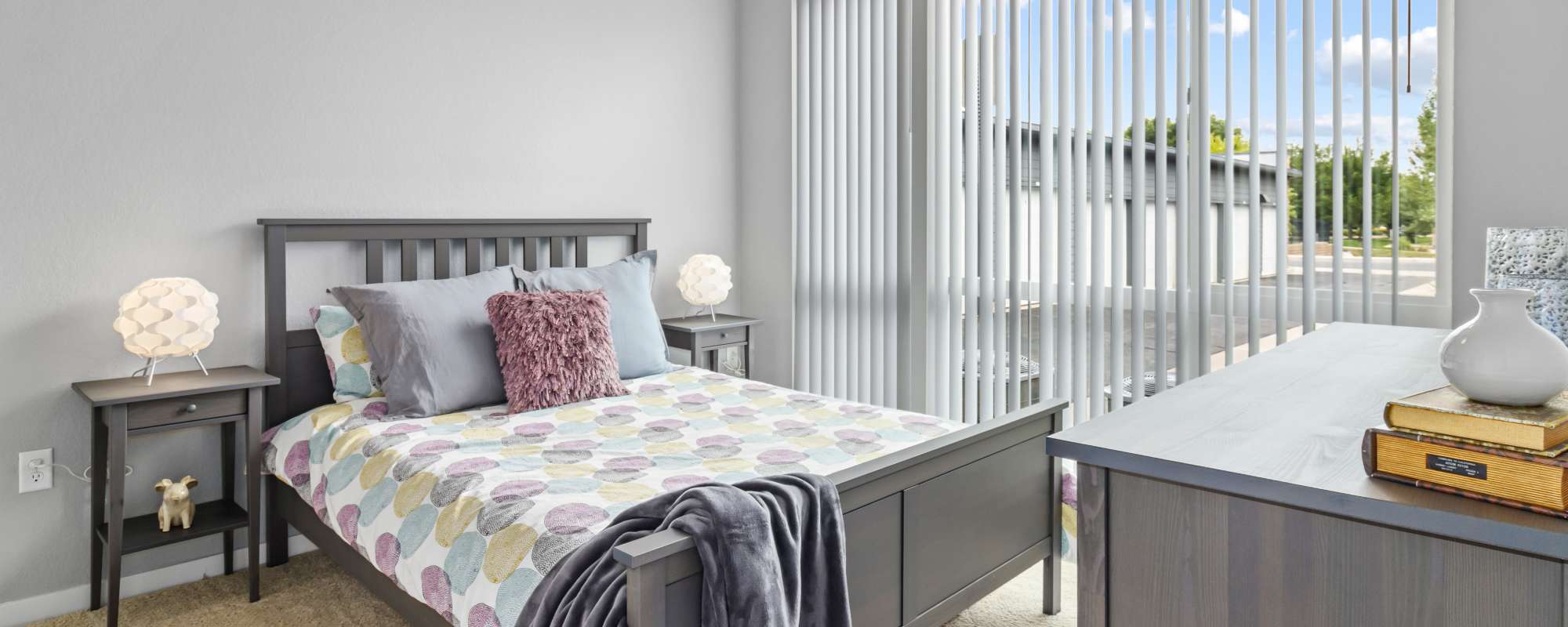 Spacious bedroom with large window and night stand with lamp at VerraWest in Longmont, Colorado