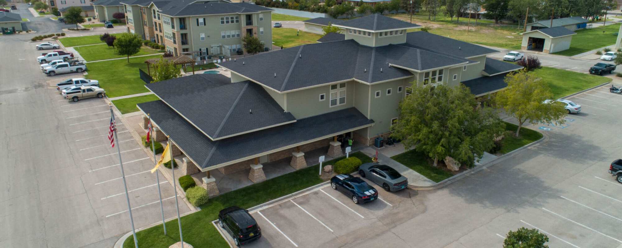 Aerial view of the community with parking cars and green lawn at Windscape Apartments in Hobbs, New Mexico