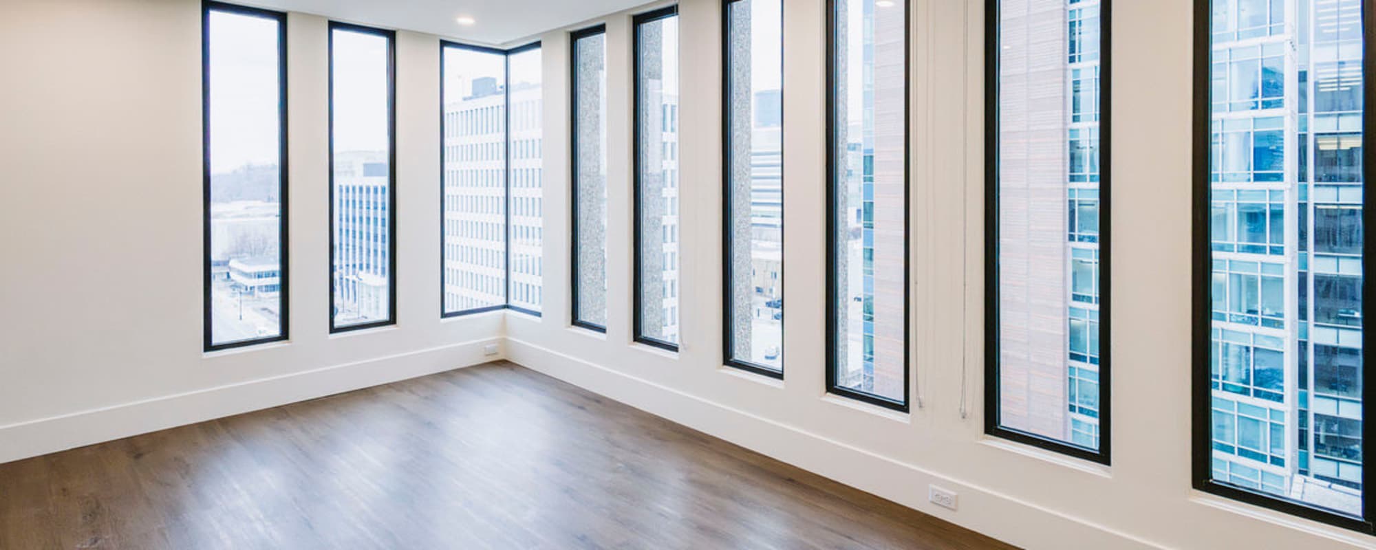 Bright apartment with large windows and wood-style flooring, open layout, and city views at Residences at 111 Lyon in Grand Rapids, Michigan