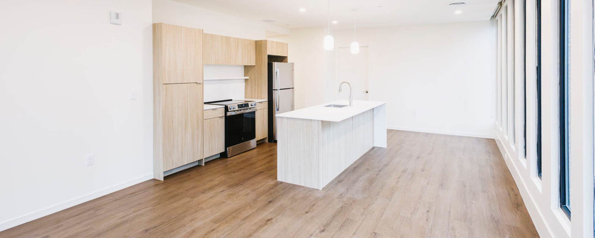 Open layout kitchen with stainless steel appliances, granite countertops, and wood-style flooring at Residences at 111 Lyon in Grand Rapids, Michigan