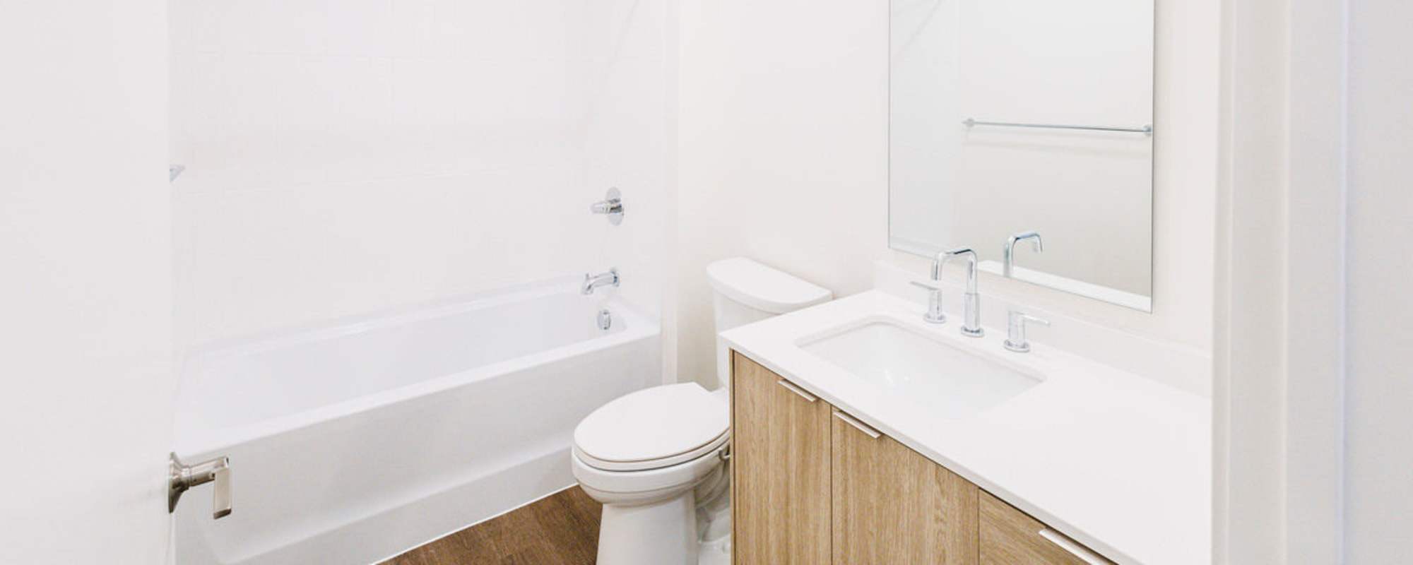 Modern bathroom with a white bathtub, wooden cabinetry, and sleek fixtures at Residences at 111 Lyon in Grand Rapids, Michigan