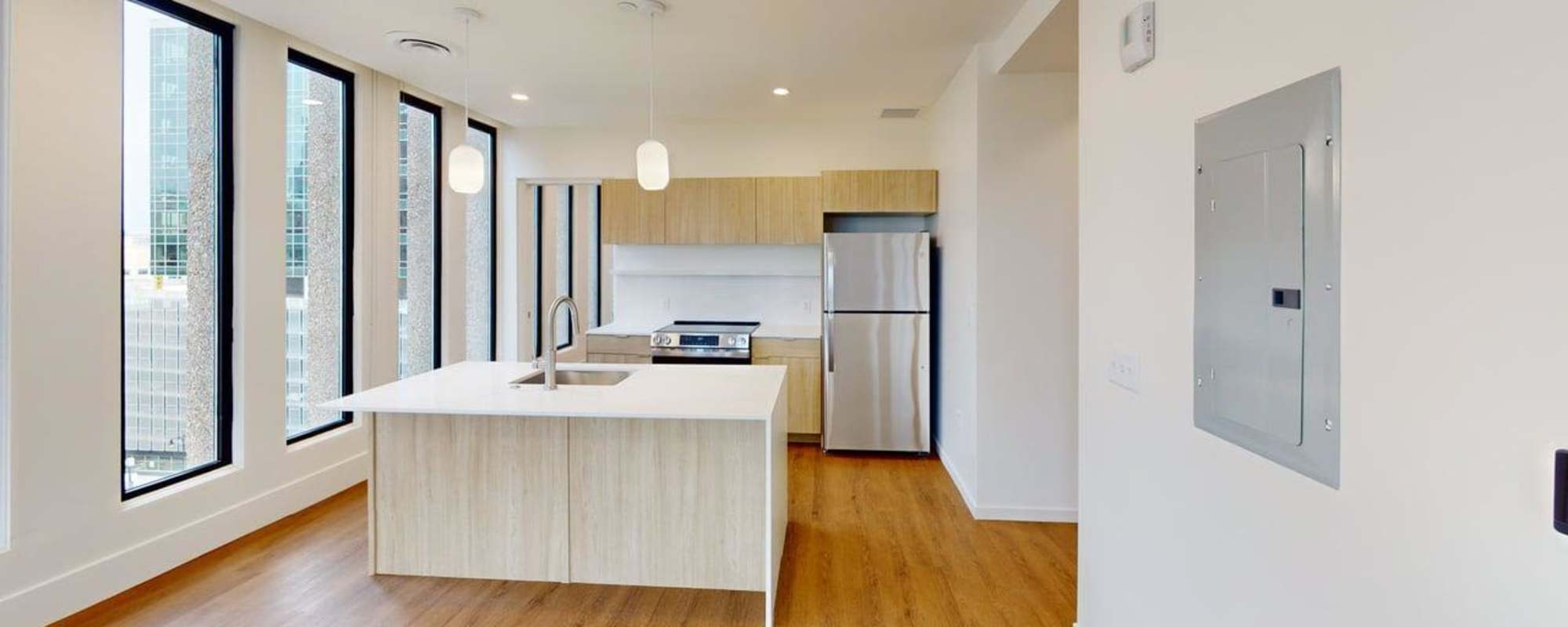 Modern kitchen with granite countertops, stainless steel appliances, and wood-style flooring. Bright, open layout with large windows at Residences at 111 Lyon in Grand Rapids, Michigan