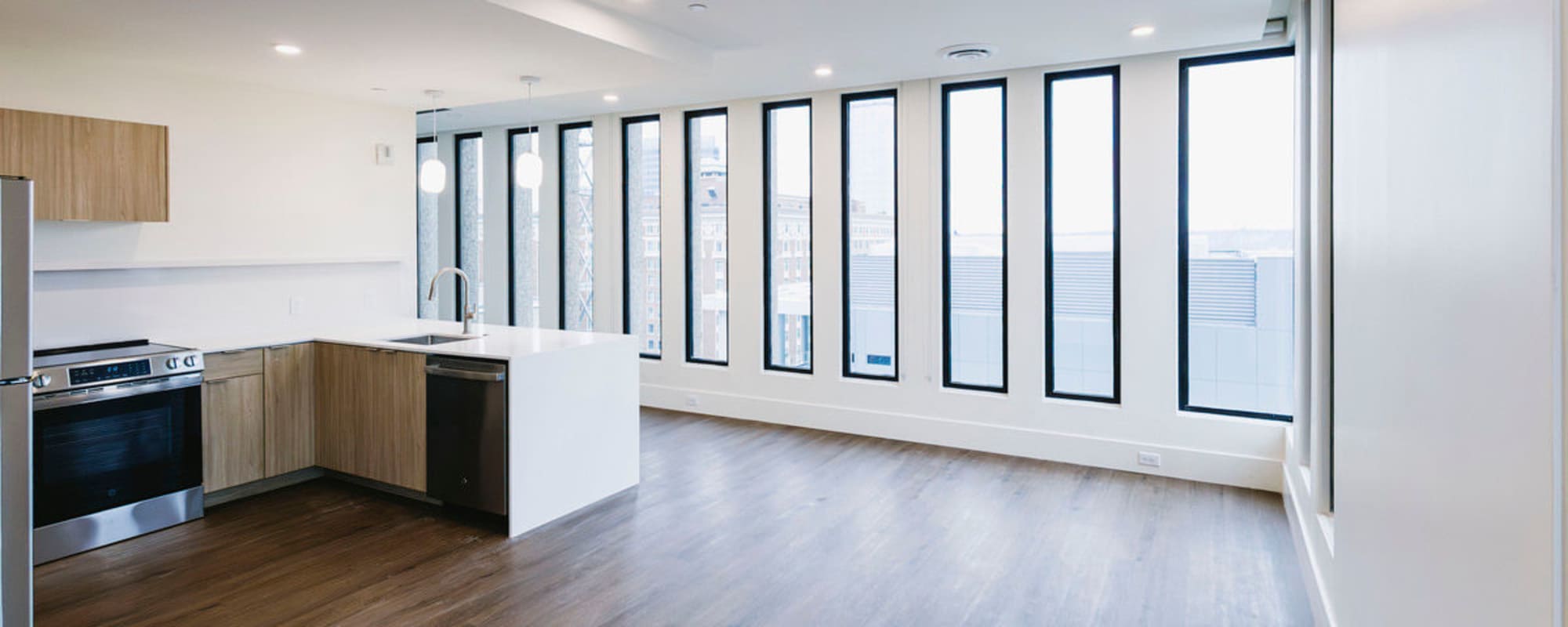 Modern kitchen with stainless steel appliances, granite countertops, and wood-style flooring in open layout at Residences at 111 Lyon in Grand Rapids, Michigan