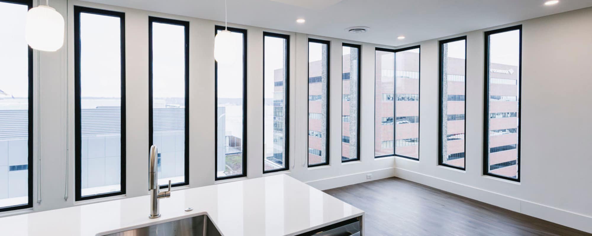 Bright kitchen with granite countertops, stainless steel appliances, and large windows showcasing city views at Residences at 111 Lyon in Grand Rapids, Michigan