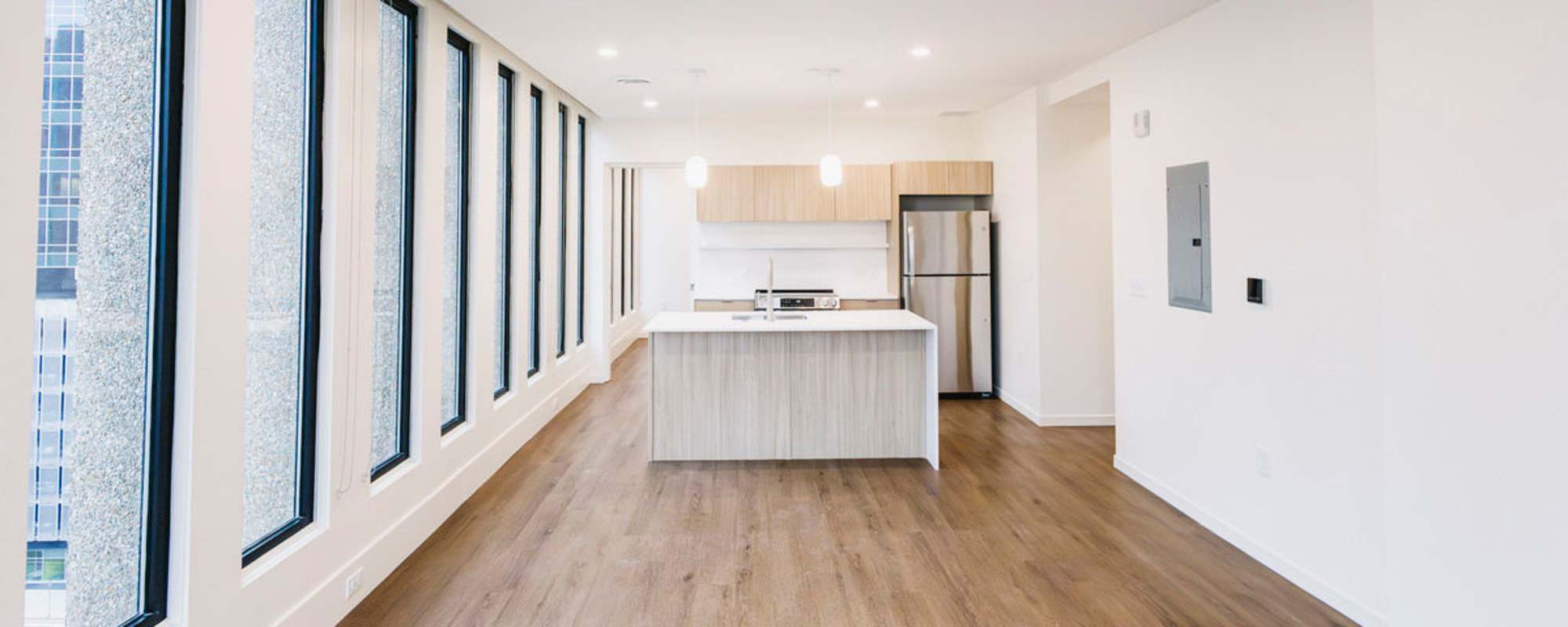 Bright open layout with wood-style flooring, modern kitchen featuring stainless steel appliances and island at Residences at 111 Lyon in Grand Rapids, Michigan