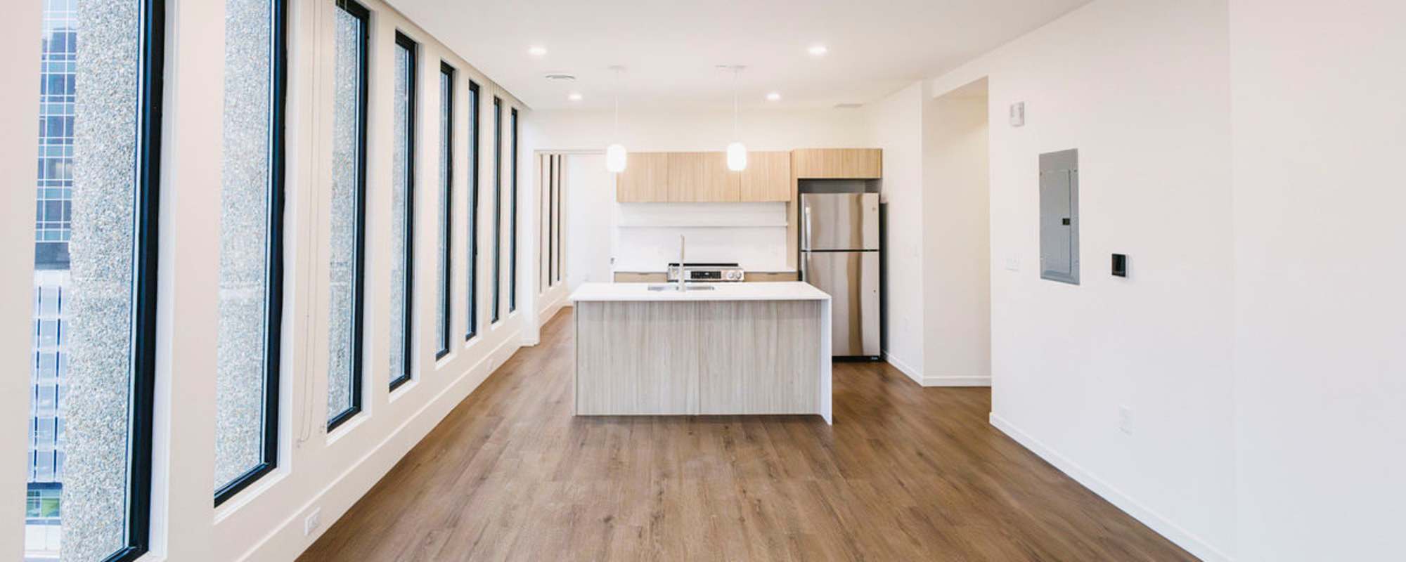 Bright open layout with wood-style flooring and modern kitchen featuring stainless steel appliances and island at Residences at 111 Lyon in Grand Rapids, Michigan