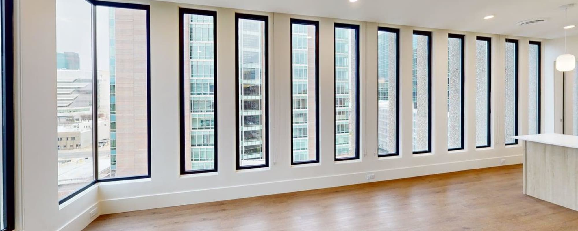 Bright open layout with large windows and wood-style flooring, modern kitchen island visible in the corner at Residences at 111 Lyon in Grand Rapids, Michigan
