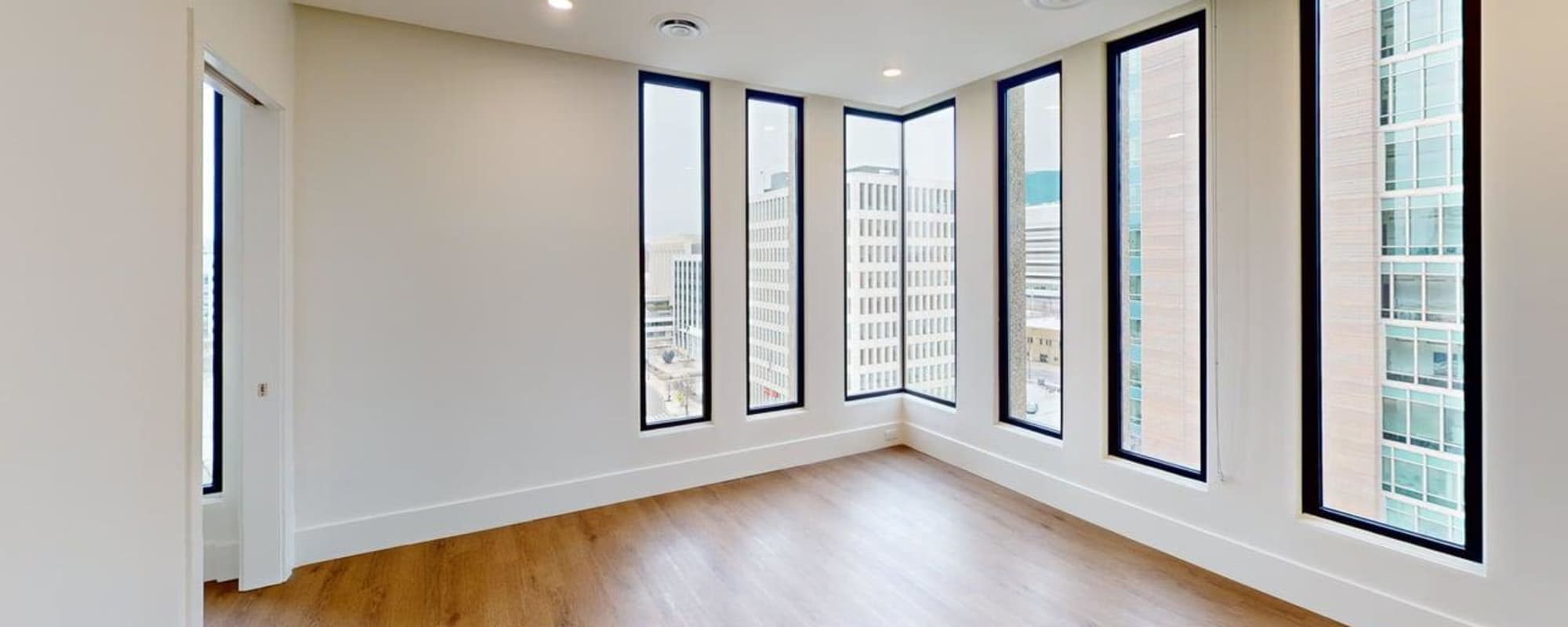 Bright room with large windows and wood-style flooring, offering city views and natural light at Residences at 111 Lyon in Grand Rapids, Michigan