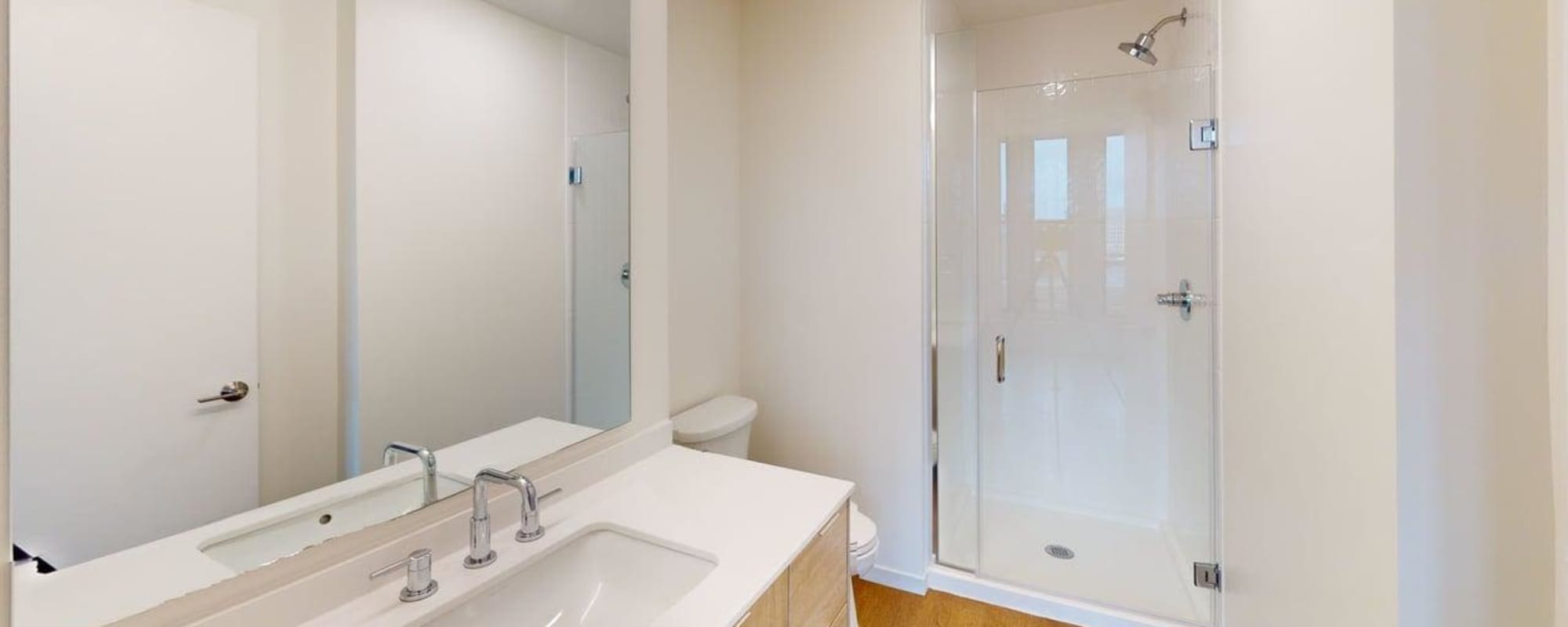 Bright bathroom featuring a glass shower, modern vanity, and wood-style flooring at Residences at 111 Lyon in Grand Rapids, Michigan