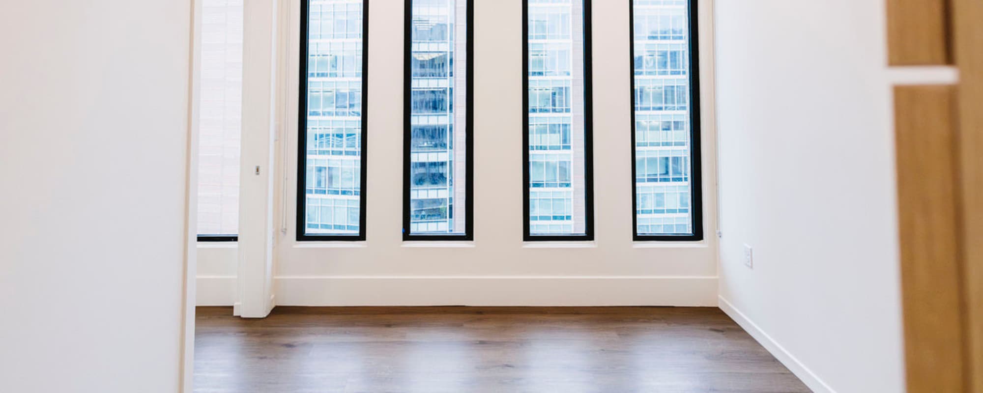 Bright room with large windows and wood-style flooring, showcasing an open layout and modern design at Residences at 111 Lyon in Grand Rapids, Michigan