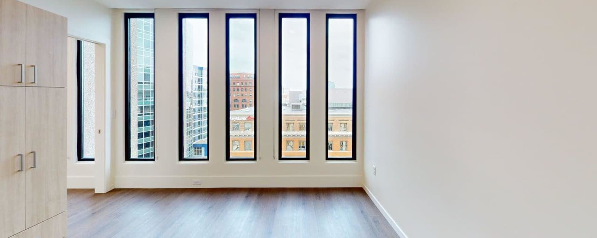 Bright apartment with large windows, wood-style flooring, and modern cabinetry at Residences at 111 Lyon in Grand Rapids, Michigan