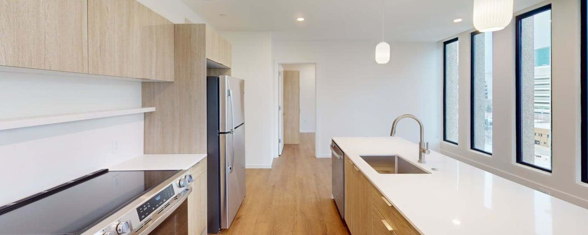 Bright open layout with wood-style flooring and modern kitchen featuring stainless steel appliances and island at Residences at 111 Lyon in Grand Rapids, Michigan