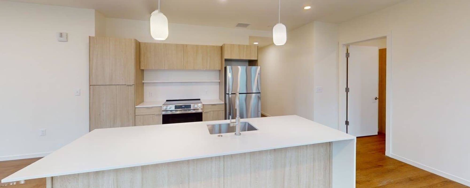 Modern kitchen with granite countertops, stainless steel appliances, and wood-style flooring at Residences at 111 Lyon in Grand Rapids, Michigan