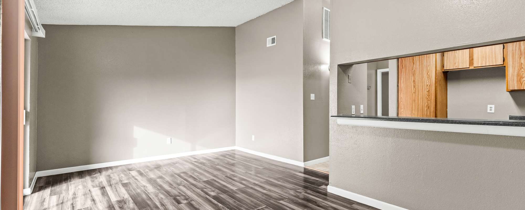 Bright living area with vinyl wood flooring, neutral colored walls, and vaulted ceilinngs at Towne East Village Apartment Homes in Converse, Texas