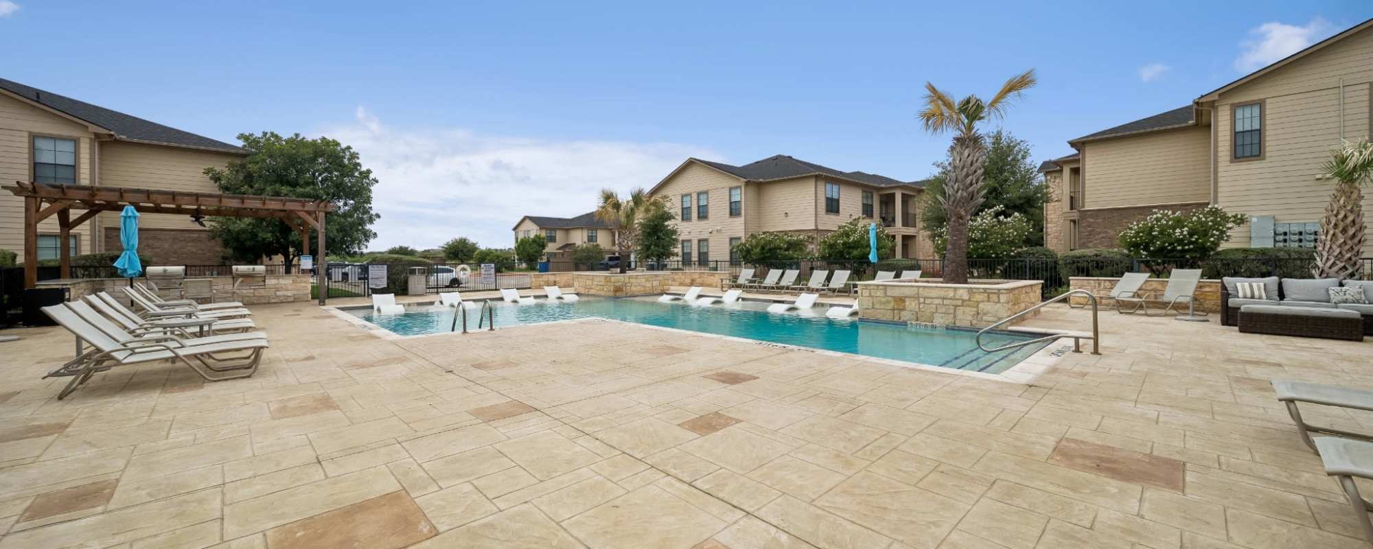 Resort-style pool area with lounge chairs at Vistas at Red Creek in San Angelo, Texas