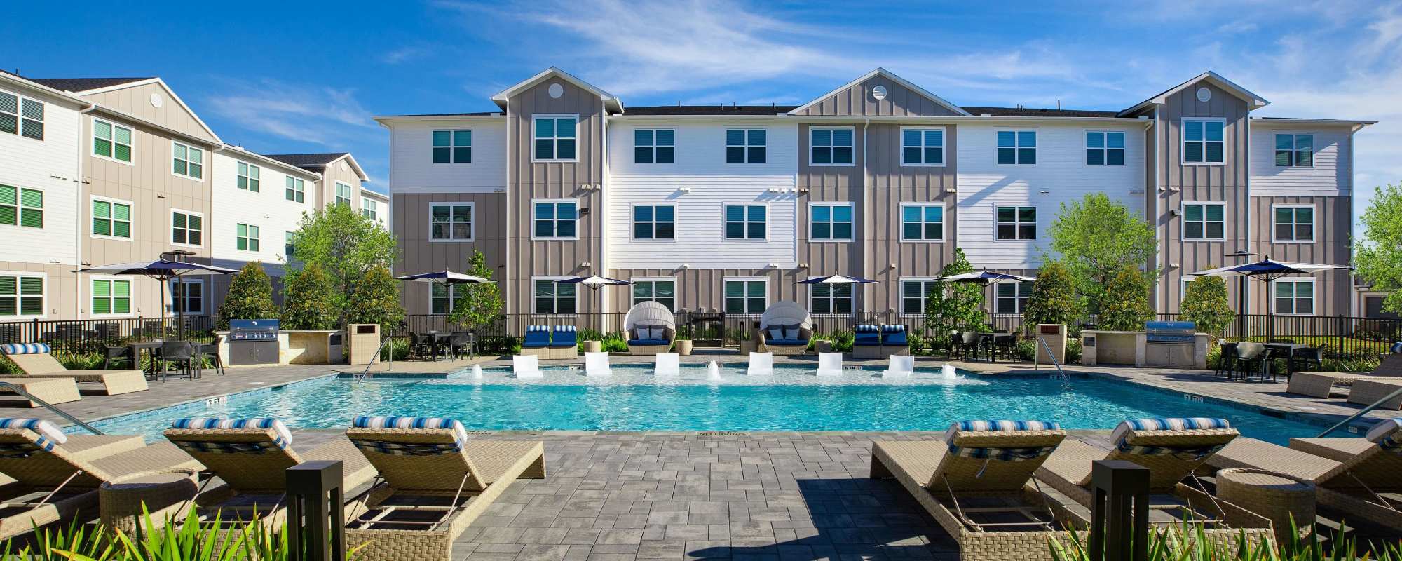 Resort-style pool with lounge chairs at August Friendswood in Friendswood, Texas