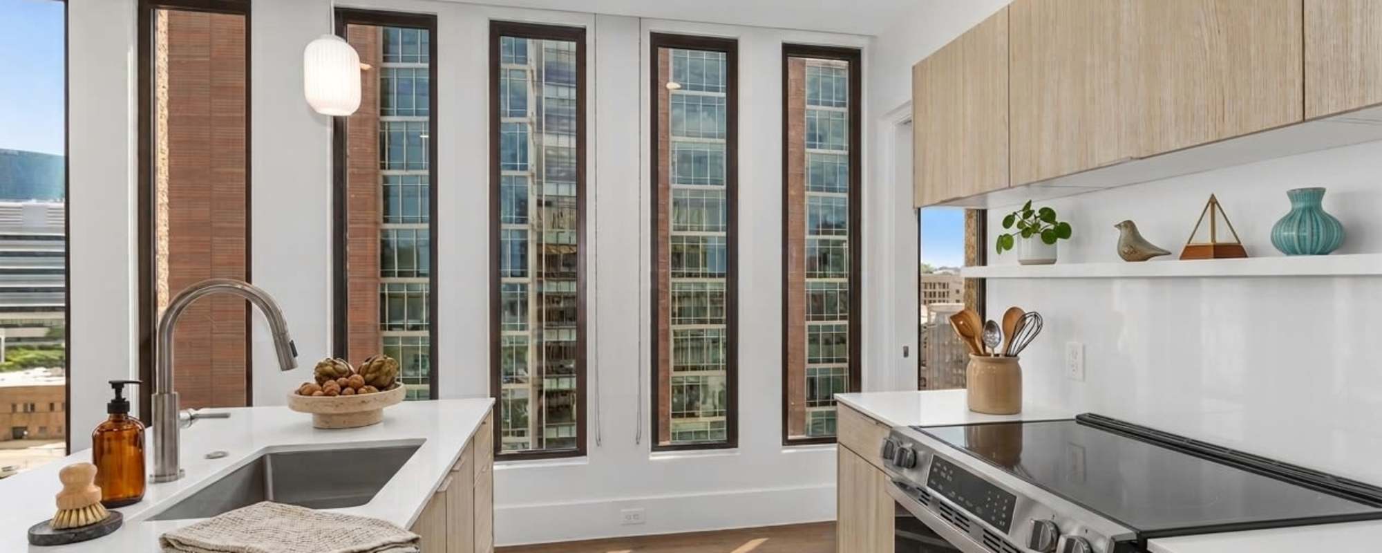 Bright kitchen with granite countertops, stainless steel appliances, and large windows showcasing city views at Residences at 111 Lyon in Grand Rapids, Michigan