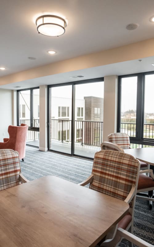 Resident recreation room with large windows and balcony access at The Pillars of Lakeville in Lakeville, Minnesota
