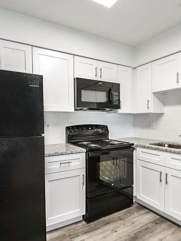 Kitchen with a black appliances and white cupboards at Woodlake Villas in Orlando, Florida
