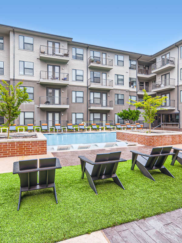 Community pool with chaise lounge seating and private cabanas at Factory Design District in Dallas, Texas
