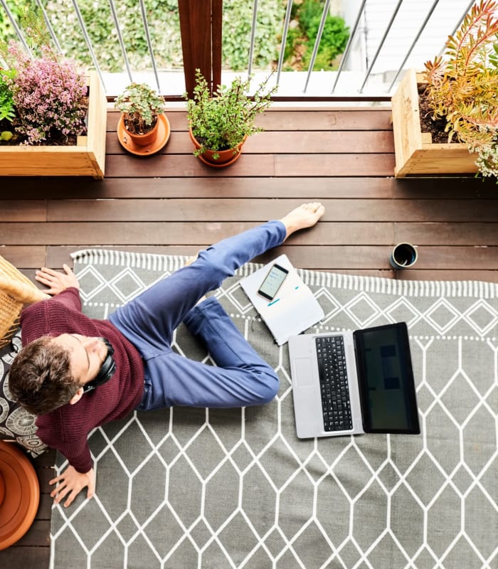 Resident relaxing on the floor at home with his laptop at Chisholm Pointe in Oklahoma City, Oklahoma