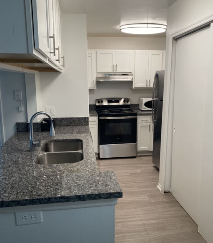 Galley kitchen with white cabinets, granite counters and stainless appliances at Huntington Reserve in Sanford, Florida