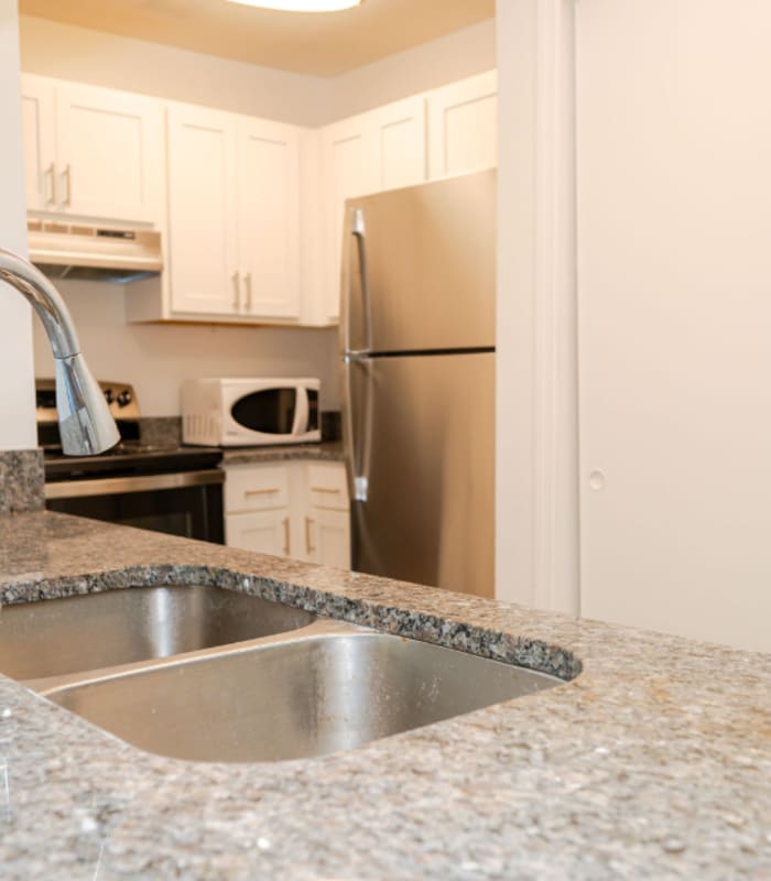 Granite counter with stainless sink leading to kitchen with white cabinets at Huntington Reserve in Sanford, Florida