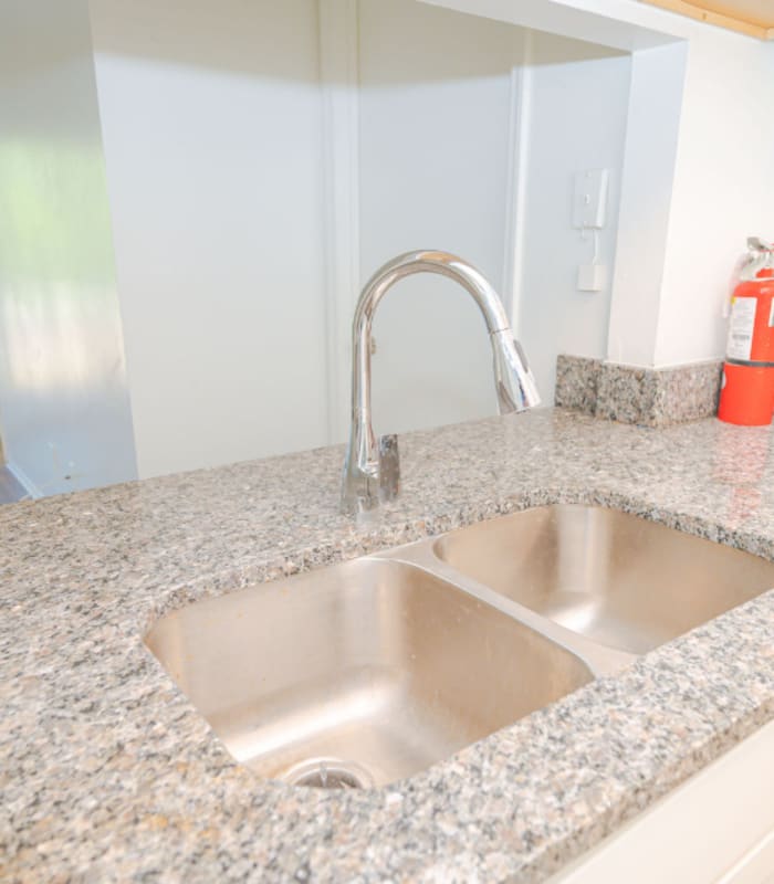 Granite counter with stainless double sink, faucet and fire extinguisher at Huntington Reserve in Sanford, Florida