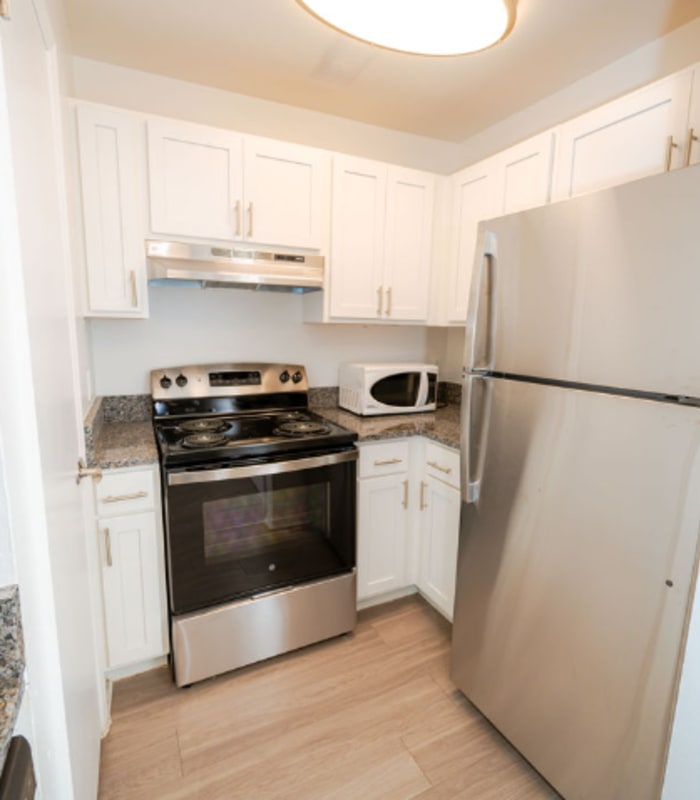 Galley kitchen with white cabinets, stainless range, microwave and refrigerator at Huntington Reserve in Sanford, Florida