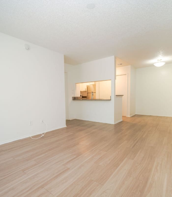 Empty living room with wood-look flooring opening to kitchen pass-through at Huntington Reserve in Sanford, Florida