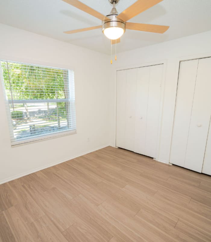 Empty bedroom with ceiling fan, window and two double-door closets at Huntington Reserve in Sanford, Florida