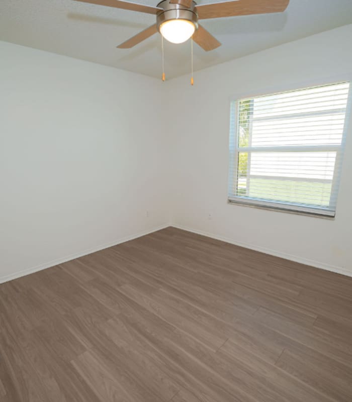 Empty bedroom with ceiling fan and window overlooking greenery at Huntington Reserve in Sanford, Florida