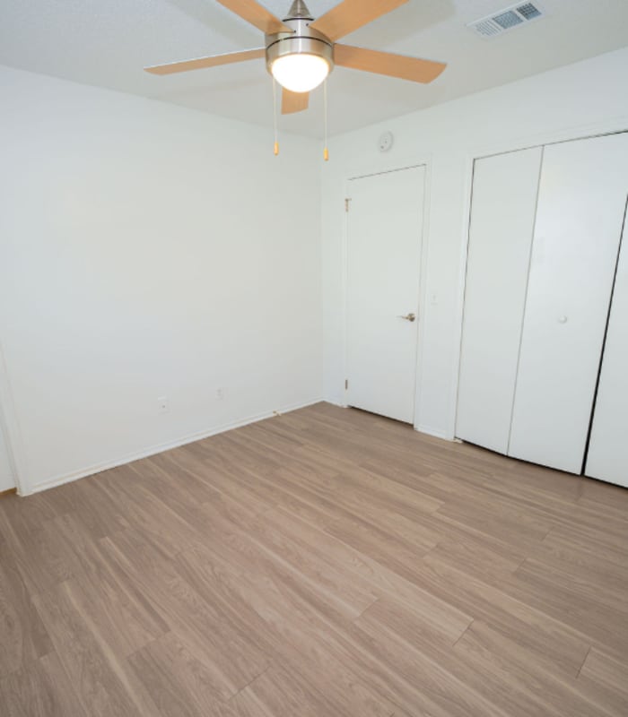 Empty bedroom with ceiling fan, closet doors and single door at Huntington Reserve in Sanford, Florida