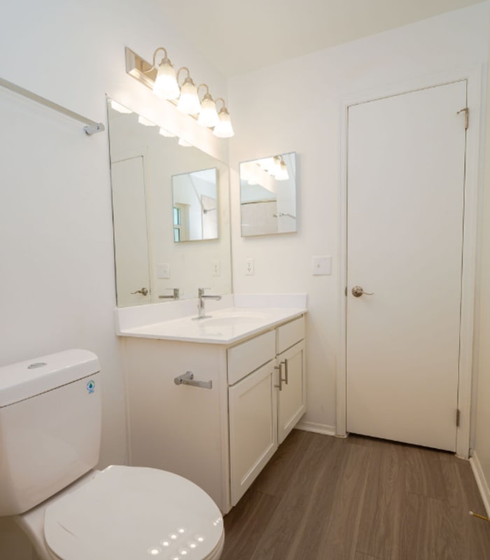 Bathroom with tan tile tub surround, white toilet and vanity with dark hardware at Huntington Reserve in Sanford, Florida