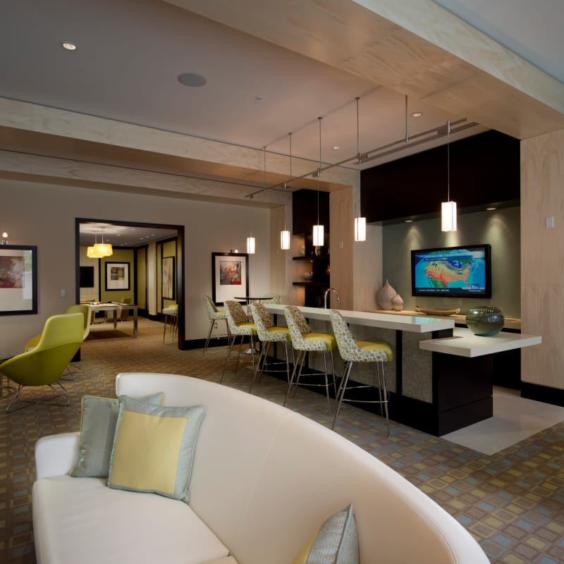 A modern clubhouse with bar seating and a flat-screen TV at Solaire 1150 Ripley in Silver Spring, Maryland