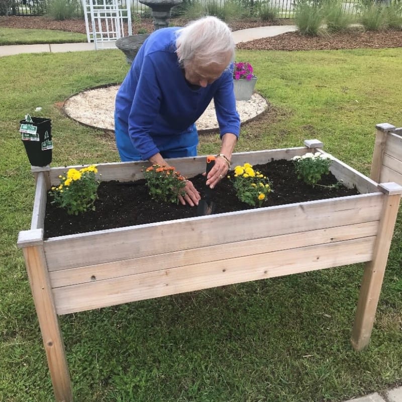 Resident planting flowers in an outdoor planterbox at The Clinton Presbyterian Community in Clinton, South Carolina