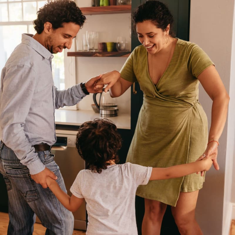 Two parents dancing with their child at home at South Meadows in Rome, Georgia