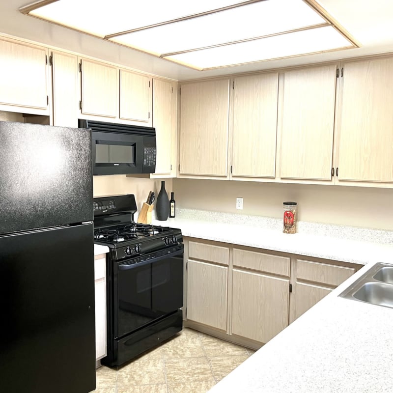 Kitchen with black appliances at Peppertree Place Apartments in Riverside, California