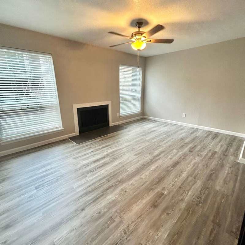 Spacious living room with windows and ceiling fan at Athena Garden Apartments in Athens, Texas