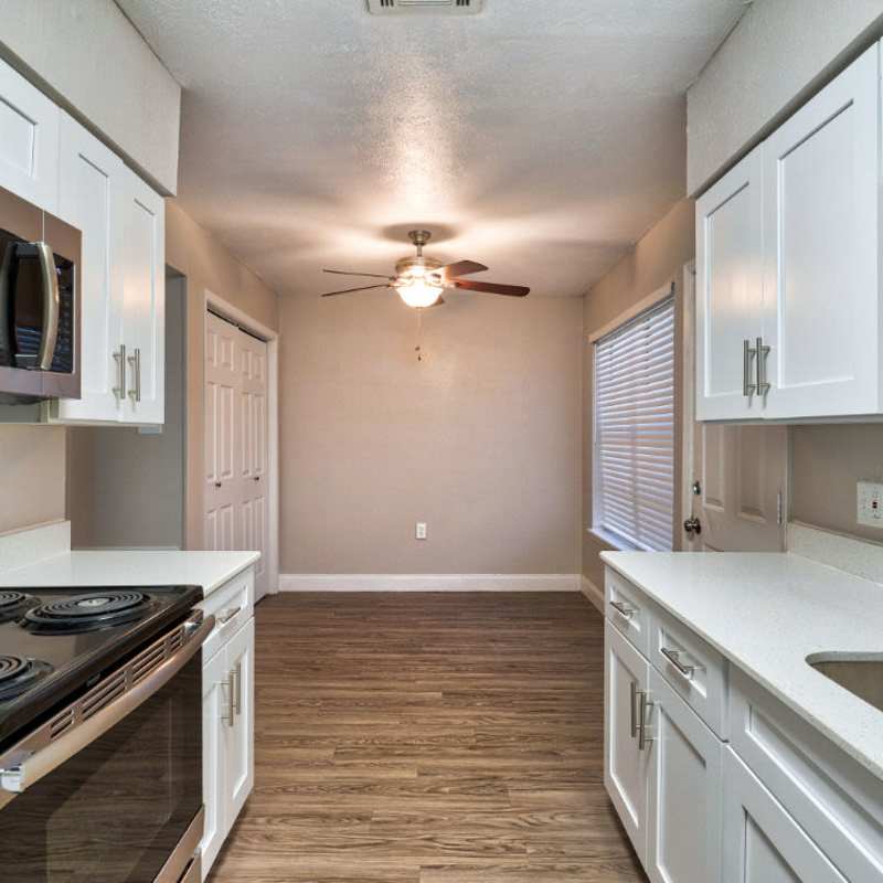 Fully equipped kitchen with granite countertops stainless steel appliances like a refrigerator, stove, and drawer microwave at Troup Townhomes in Troup, Texas
